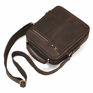 Detail shot of vintage dark brown leather shoulder bag with durable canvas strap and metal zippers.