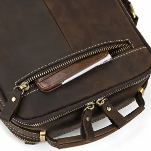 Detailed closeup of retro brown genuine leather messenger bag zipper and reinforced handle texture.
