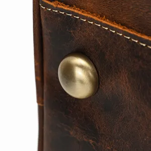 Vista detallada de bolsa de viaje de cuero genuino con remache metálico vintage y costuras finas.