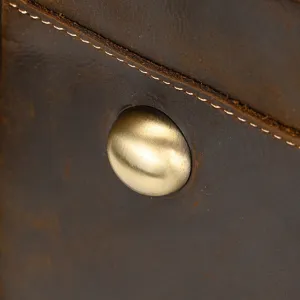 Primer plano de detalle de bolsa de viaje de cuero vintage, con remache de latón y costuras.