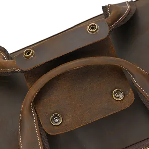 Primer plano del asa de bolsa de viaje de cuero vintage marrón y broche de metal.