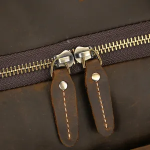 Detalle de bolsa de viaje de cuero con cremallera metálica duradera y tiradores.