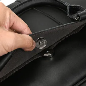 Detailed shot of men's leather briefcase magnetic snap button, premium cowhide material.
