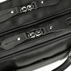 Black leather briefcase detail showing dual zippers, metal rivets, and fine stitching texture.