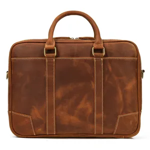 Brown leather briefcase closeup showing cowhide texture, dual handles and metal hardware.