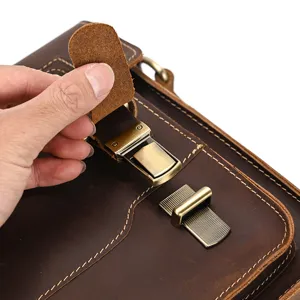 Detail shot of a vintage crazy horse leather messenger bag metal clasp hardware close-up.