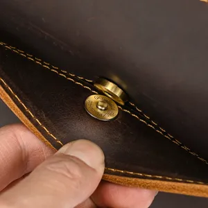 Detailed view of vintage crazy horse leather bag magnetic snap hardware and contrast stitching.