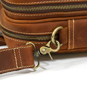 Close-up detail of brown leather messenger bag featuring durable metal hardware and stitching.