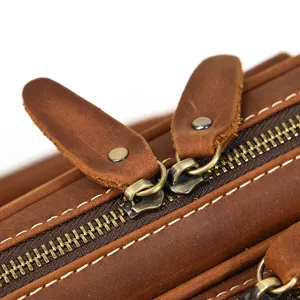 Close-up detail of premium brown genuine leather men business briefcase zipper and pull.