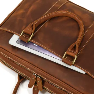 Detailed close-up of brown leather briefcase handle and zipper pocket, genuine cowhide texture.
