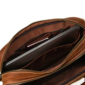 Close-up interior detail of brown leather briefcase, showing multi-compartment laptop storage.