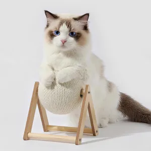 Close-up of a cute cat playing with a natural sisal scratching ball on a stable wooden stand.