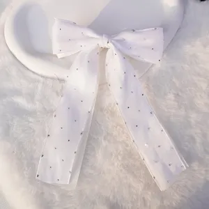Primer plano de un pasador de pelo con lazo blanco de doble capa y diamantes de imitación