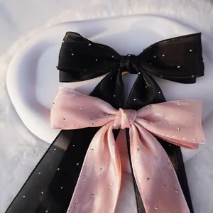 Detalle de pinzas para el cabello con doble lazo, brillantes de estrás y cintas largas.
