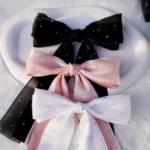 Detalle de elegantes pinzas para el pelo con doble lazo estrellado y cintas largas.