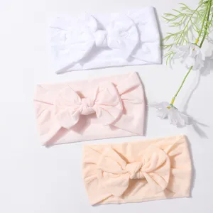 Detailed view of three soft nylon bow headbands in white, pink, and peach colors.
