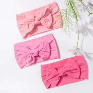 Detailed macro shot of three soft nylon baby bow headbands in various shades of pink.
