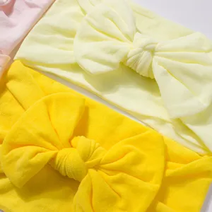 Macro detail of soft nylon bow headbands for babies in bright and pale yellow