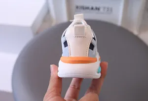 Macro detail view of children's breathable sneaker heel with orange and blue accents.