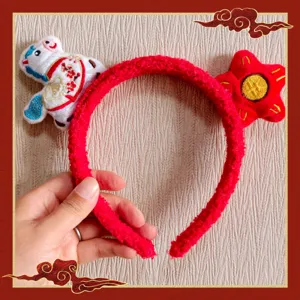 Close-up of red plush headband with cute zodiac horse and star details for festival.