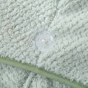 Gros plan détaillé du bonnet de bain en polaire corail douce avec texture et bouton de fixation.