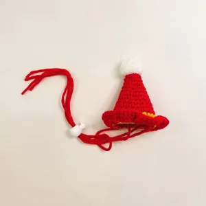 Detailed shot of handmade red knitted pet hat with white pom-pom and yellow brim for small pets.