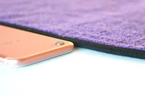 Close-up detail of the thick purple microfiber car cleaning towel featuring black stitched edges.