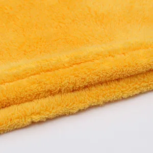 Close up detail of soft yellow coral fleece towel fabric showing thick and absorbent plush texture.