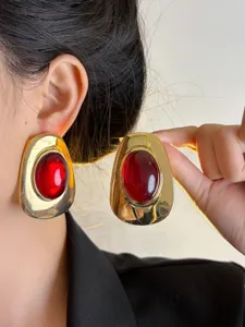 Vintage style chunky gold metal earrings featuring bold red resin stones. Detail shot.