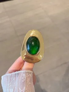 Close-up detail of vintage green stone metal accessory, retro textured surface design.