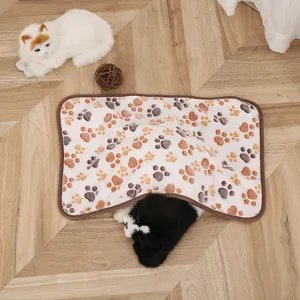 Detailed shot of soft coral fleece pet blanket with cute paw print pattern on wooden floor.