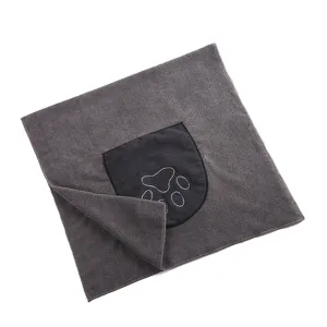 Detalle de toalla de microfibra gris para mascotas con bolsillo y bordado de huella.