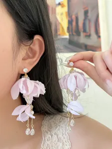 Close-up detail of purple fabric flower dangling earrings with crystals and pearls.