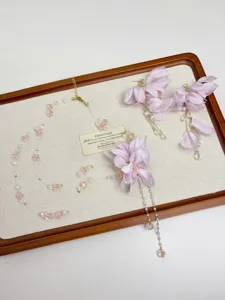 Close-up detail of purple fabric flower necklace and matching fresh floral earrings set.