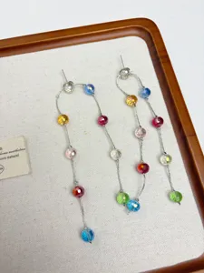 Detailed shot of long dangling earrings featuring vibrant multicolored faceted beads on fine chains.
