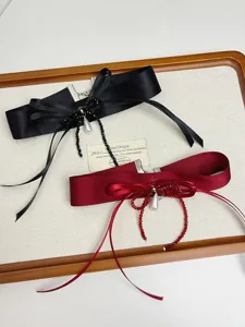 Detail van retro strik choker ketting met satijnen lint, kristalen kralen en parelhang.