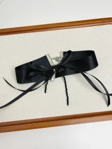 Detailopname van vintage zwarte ribbon choker halsketting met parel en strik accent.
