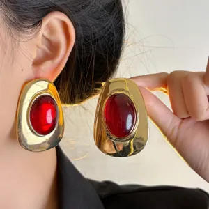Vintage European style chunky gold metal earrings with large red resin statement studs.