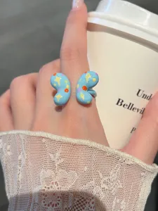 Close-up detail of cute blue drip-oil ring featuring yellow stars and colorful dots.