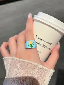 Close-up detail of a cute light blue drip oil flower ring worn on hand, stylish aesthetic.