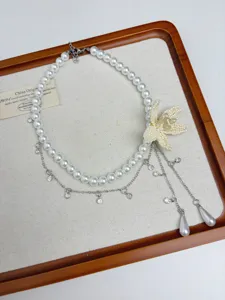 Detailed close-up of layered white pearl necklace with beaded flower and rhinestone chains.