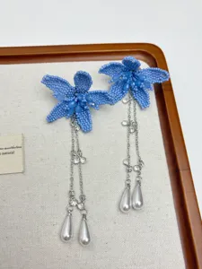 Blue beaded flower earrings with long silver chains and pearl pendants, delicate boho jewelry detail.