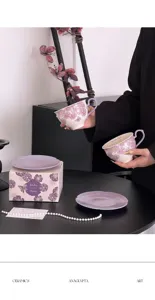 Detalle de taza de café de cerámica violeta con patrón floral y platillo elegante.