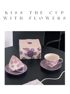 Vista detallada del juego de taza de cafe y platillo de ceramica floral morada.