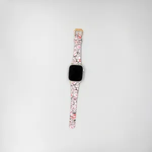 Primo piano dettaglio del cinturino in pelle floreale per smartwatch, stampa rosa.