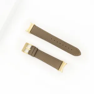 Detail view of a taupe genuine leather watch strap featuring elegant gold hardware and stitching.