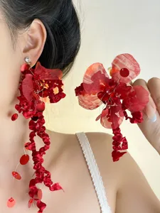 Primo piano di orecchini pendenti rossi in chiffon con fiori, paillettes e design elegante.