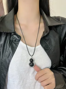 Close-up view of the chic black gourd pendant necklace worn on neck, showcasing details.