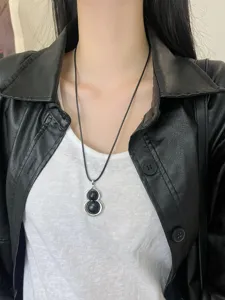 Black gourd pendant long necklace detail shot, elegant and chic fashion accessory for women.
