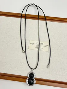Detailed view of the elegant black gourd pendant necklace, showcasing fine metallic craft and cord.